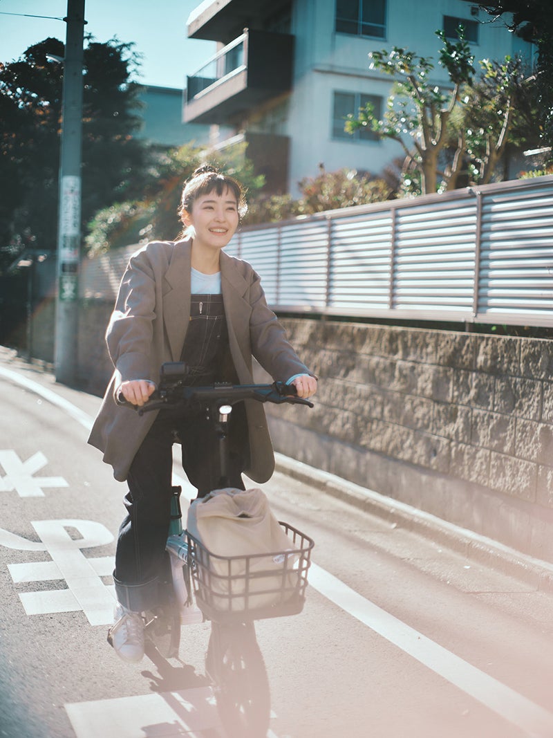 自転車に乗る女優の清水みさと氏　自転車の前かごにサウナバッグが入っている