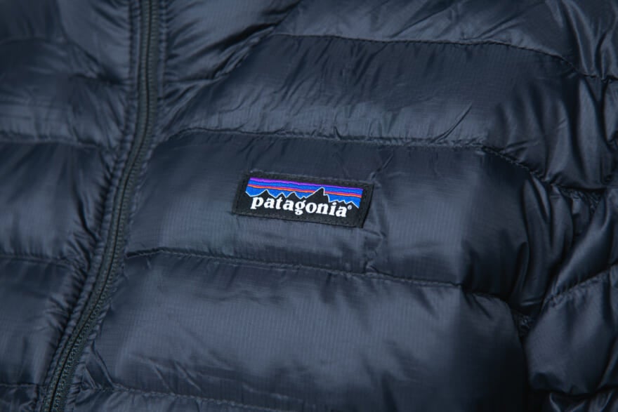 パタゴニアの黒ダウン「メンズ・ダウン・セーター・フーディ」の着用画像のロゴ