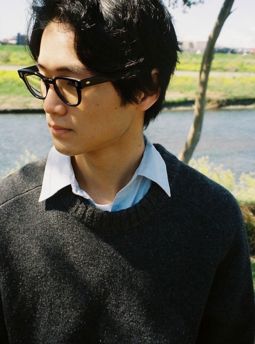 メガネをかけて川の近くに立つ、中川大輔