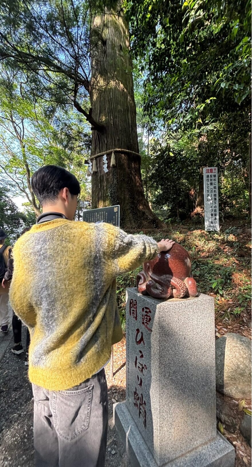 高尾山の名所「ひっぱり蛸」を撫でる石川
