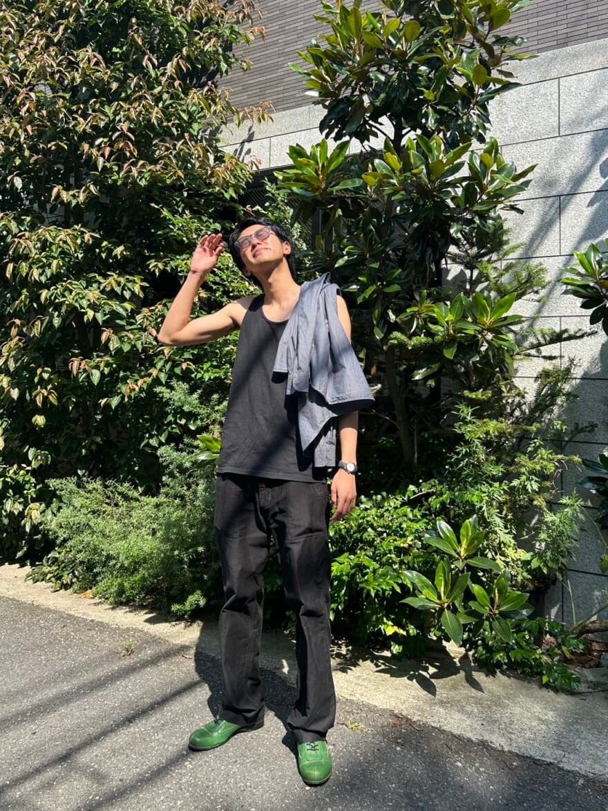 緑の前で、眩しそうに上を見上げる髙橋大翔。黒いタンクトップを着て、肩にシャツをかけている。