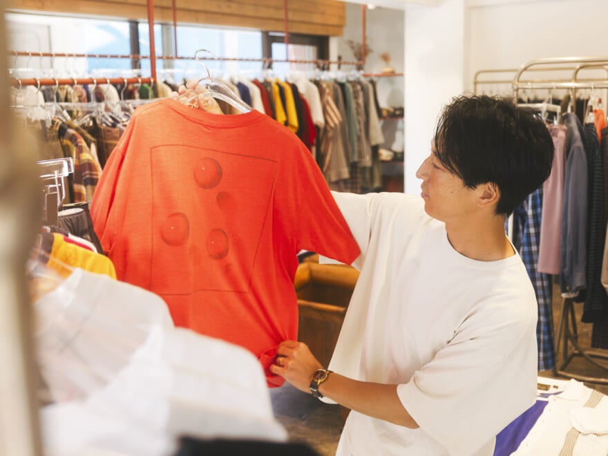 赤いTシャツを手にとる八木さん