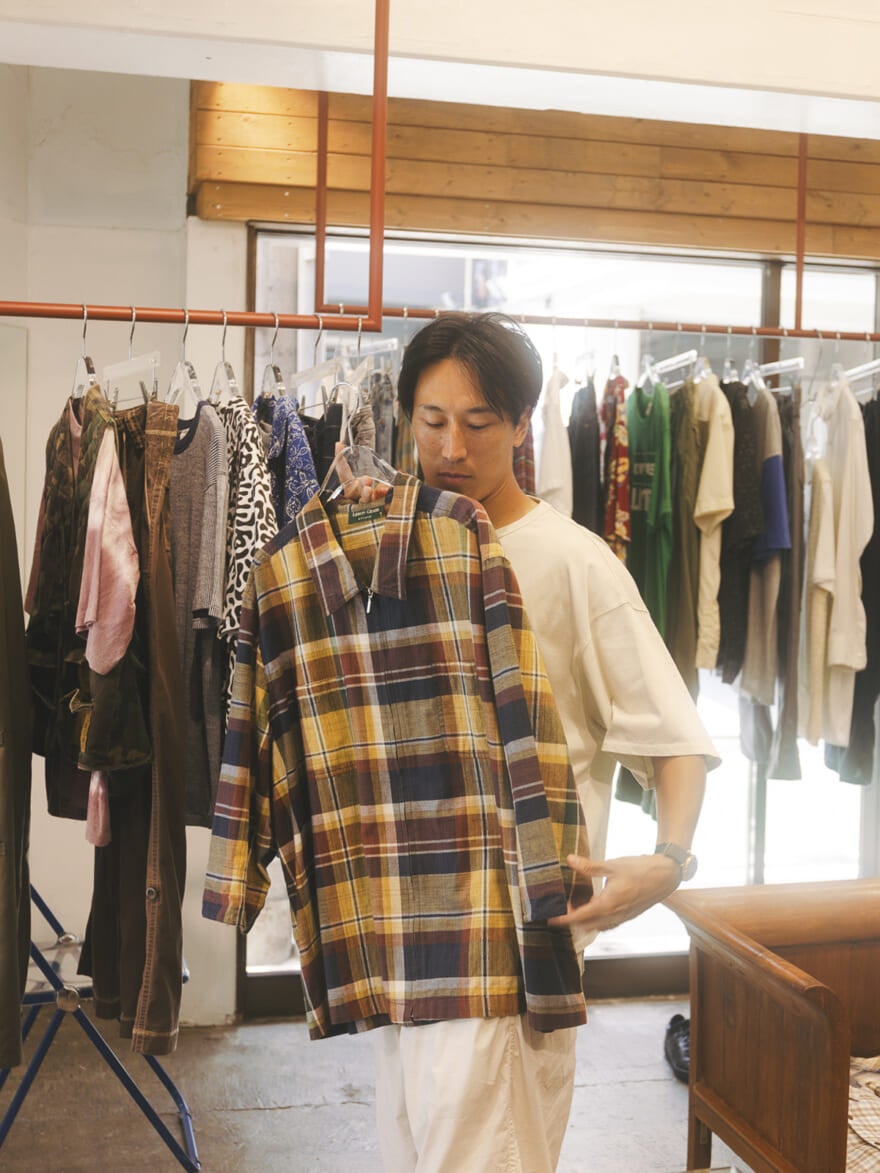 チェックの古着を体に当てる八木さん