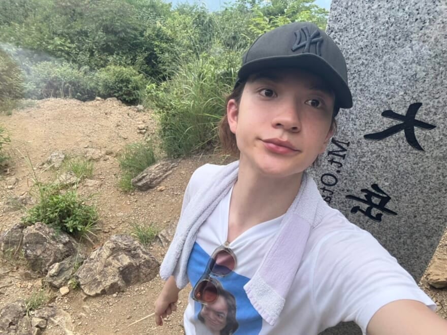 大岳山の石碑の前に立つメンズノンノモデル嵐翔真。自分の顔がプリントされたTシャツを着ている。
