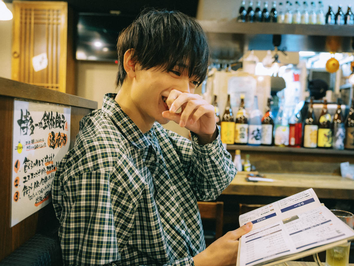 居酒屋でメニューを持ちながら微笑む水沢林太郎