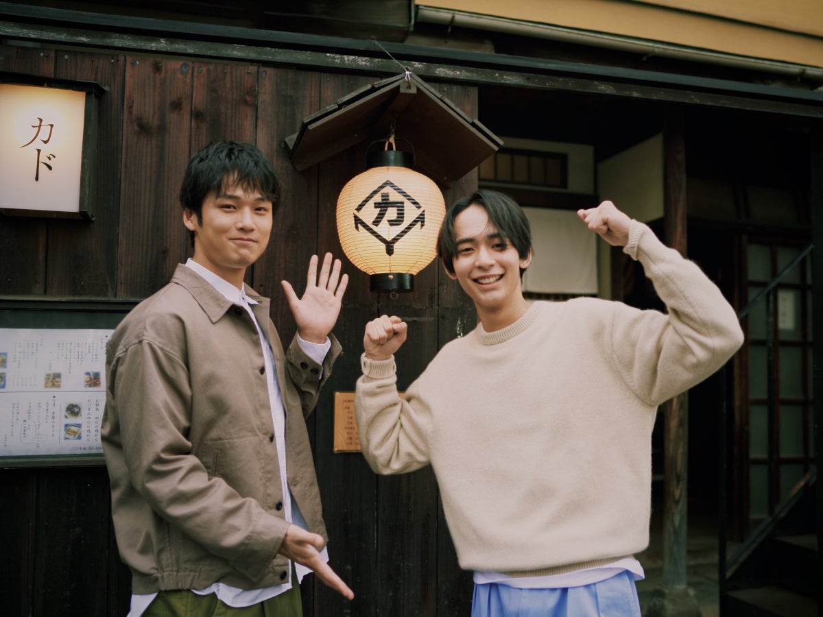 居酒屋の前でポーズをとる中川大輔と松井大奈