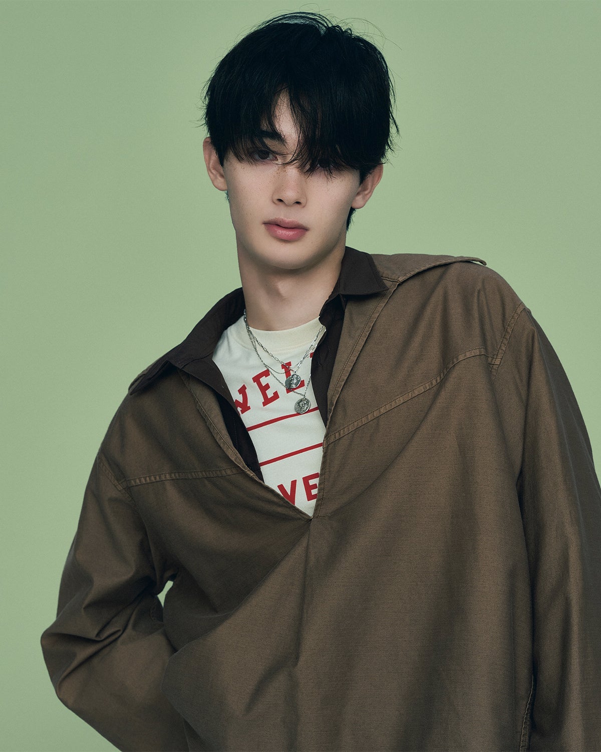 首もとから主張のあるプリントTシャツのロゴをのぞかせることで、堅さを和らげつつストリートなムードを差し込む