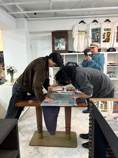 メンズノンノモデル中田圭祐と、「MRKET」店主・ランさんが、協力してシルクスクリーンを刷っている写真。中田が板を押さえ、店主が刷っている。