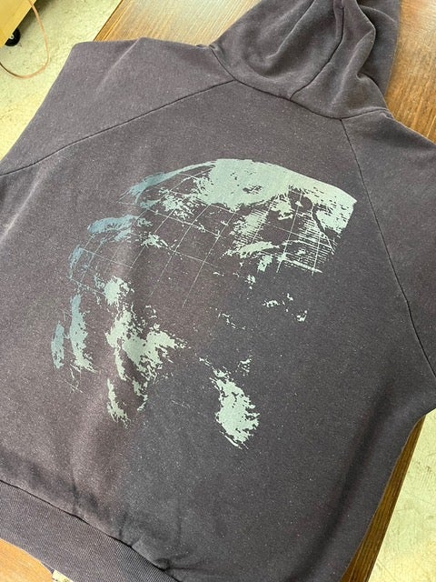 背面に地球のグラフィックが入った、グレーのパーカ