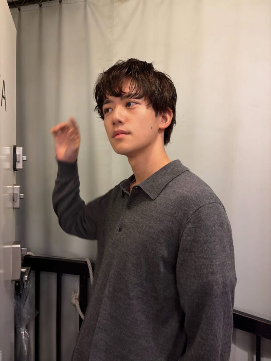 斜め上の方を見るメンズノンノモデル樋之津琳太郎。グレーニットポロを着ている。