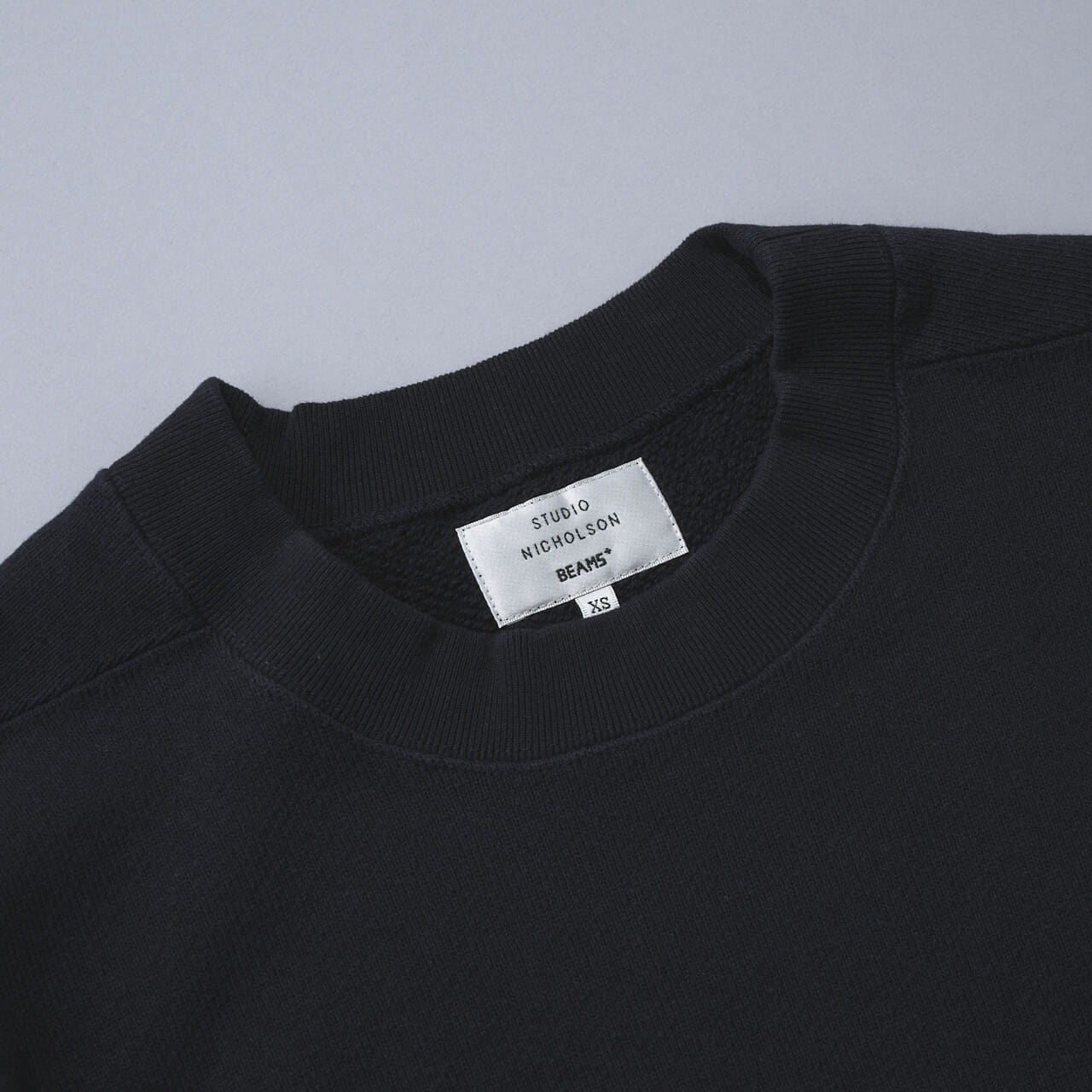 エディターが愛用するスタジオ ニコルソンとビームス プラスのネイビースウェットのタグ