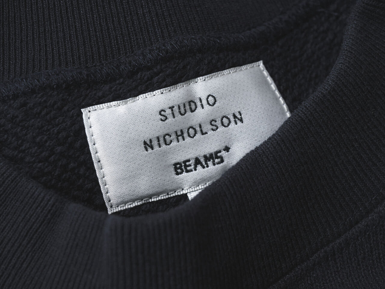 エディターが愛用するスタジオ ニコルソンとビームス プラスのネイビースウェットのタグ寄り