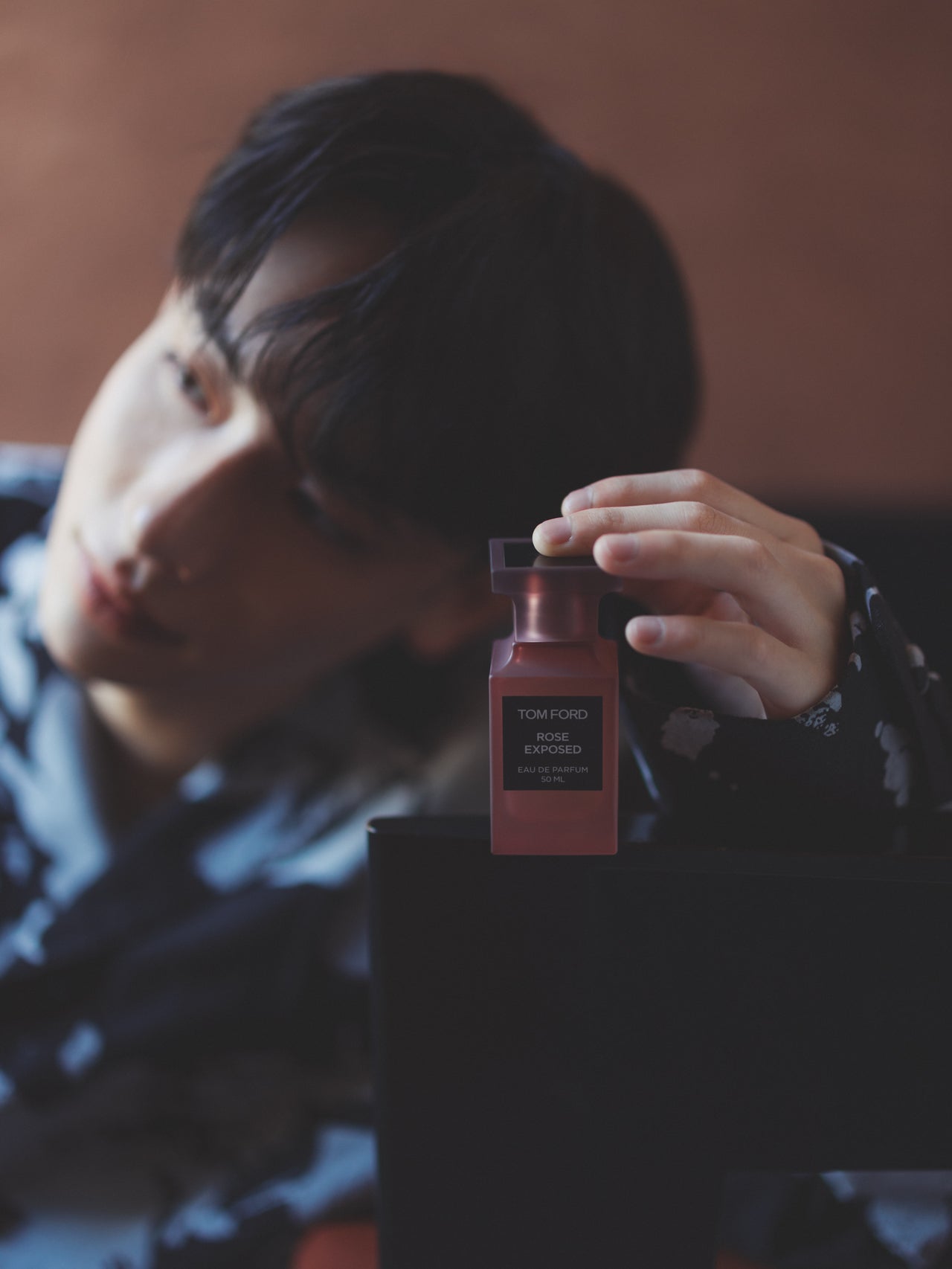 トムフォードの香水「 ローズ エクスポーズド」を手に持つよしあきさん