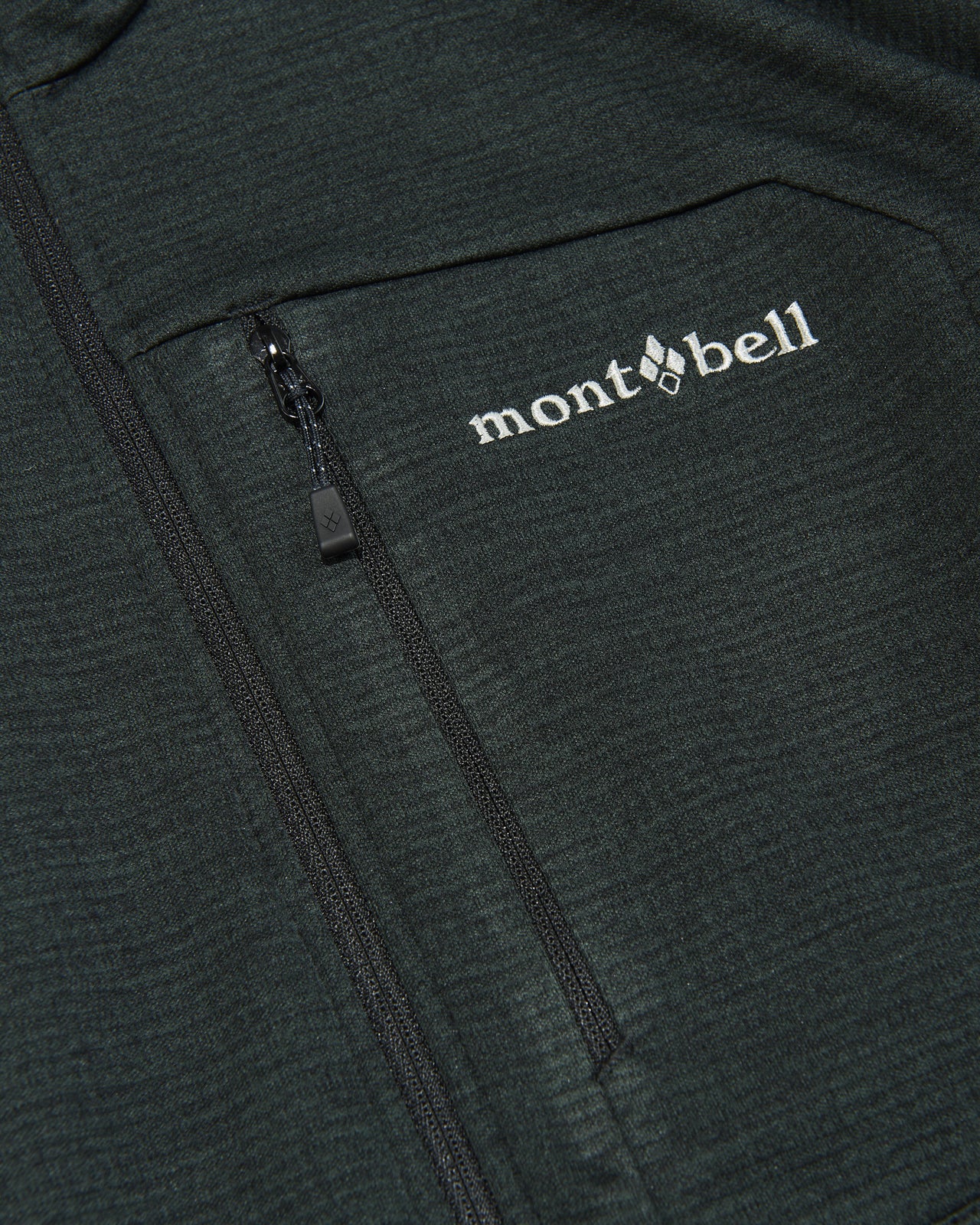 モンベルの黒いクリマグリッド ジャケットのロゴ