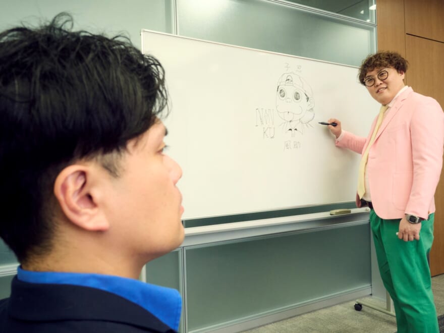 マユリカホワイトボードに絵を描く中谷さんとそれを見る阪本さん