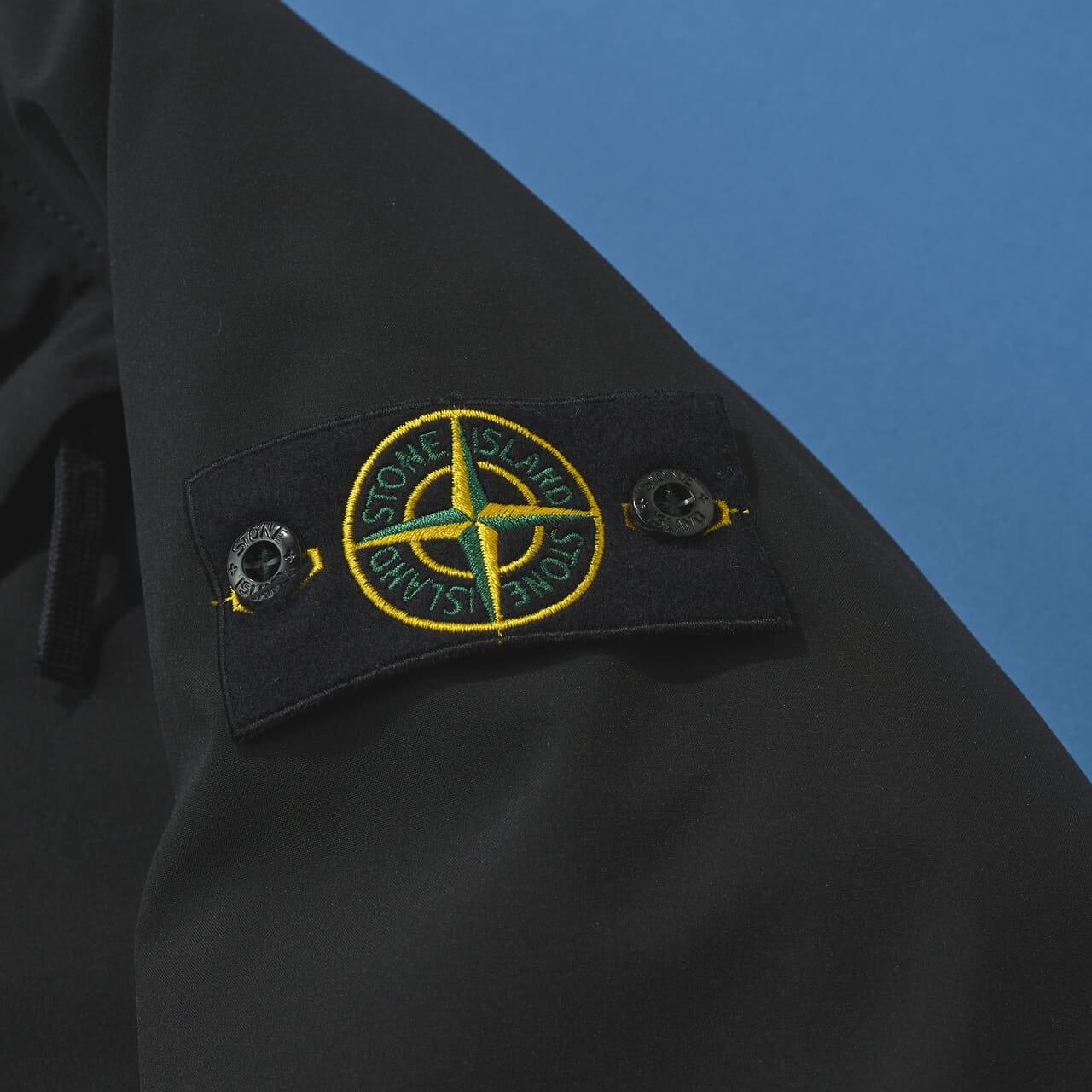 ストーンアイランドの黒い中綿ジャケットの袖ロゴ