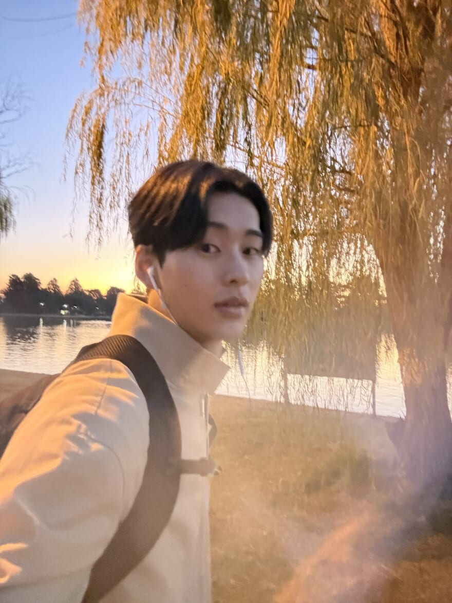 メンズノンノ石川愛大。奥に柳のように枝が垂れた木が写っている。