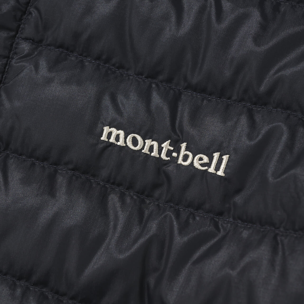 エディターが愛用するモンベルの黒い薄軽インナーダウンのロゴ寄り