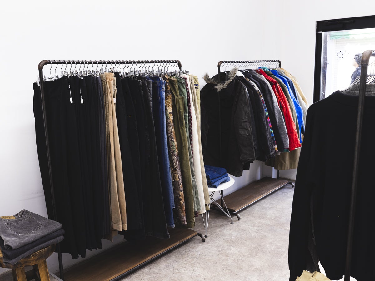 古着店シノの店内ラック。手前にパンツ、奥にアウターがかかっている。