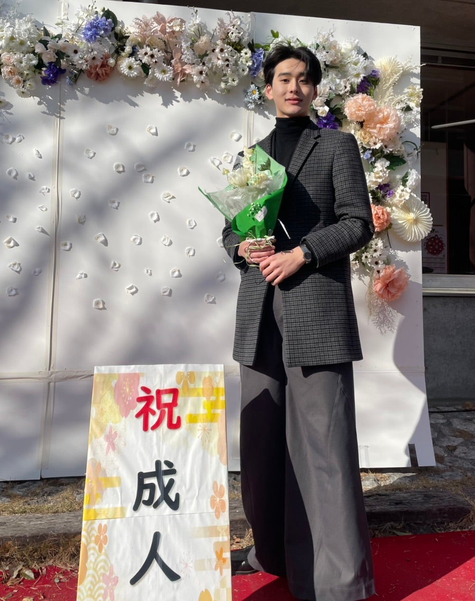 「祝 成人」の立て看板の横に立つメンズノンノモデル石川愛大