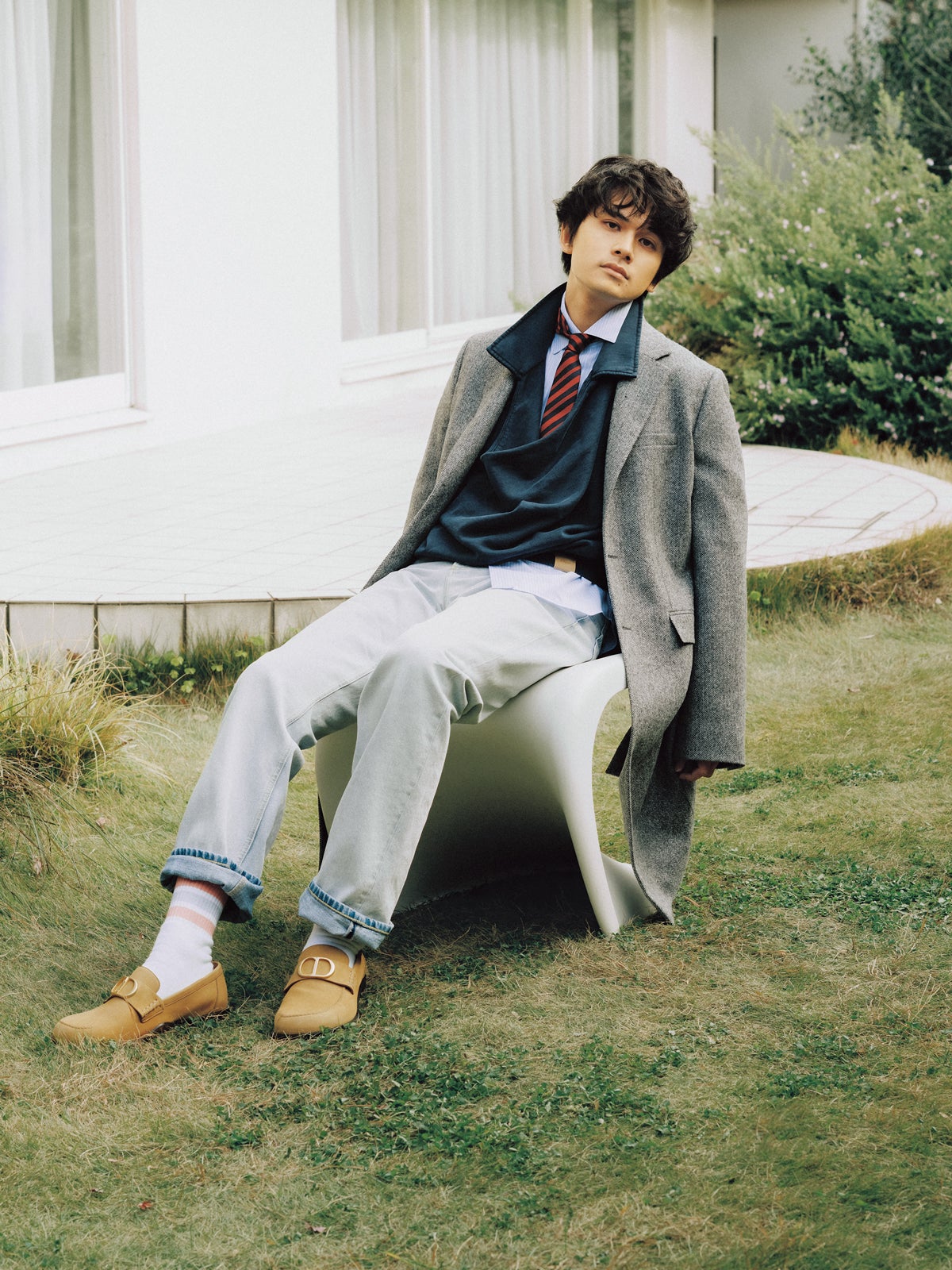 Diorの春物のロングコートとデニムを着用する俳優の北村匠海さん