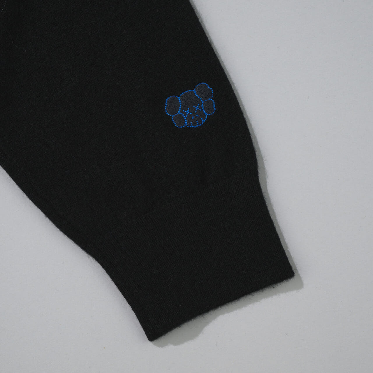 エディターが買ってよかったユニクロの愛用コラボ黒ニット／カウズ ウィンター カシミヤクルーネックセーターの袖ロゴ