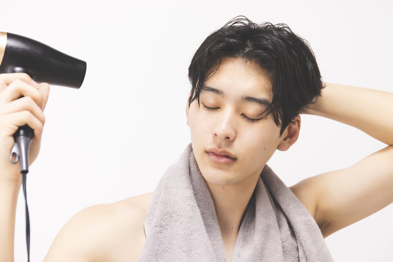 ドライヤーで髪を乾かしているメンズ