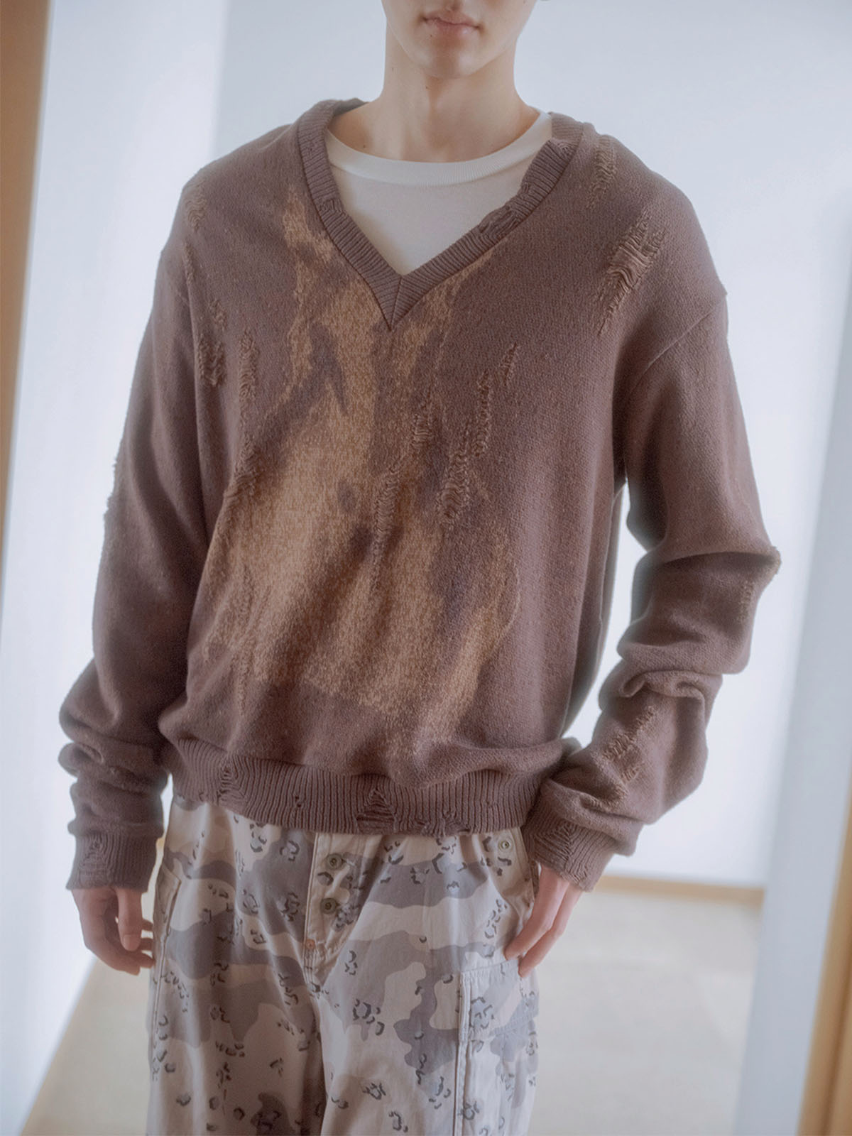 立体的な編みで表現したグラフィックが施されたダメージニットの着こなし