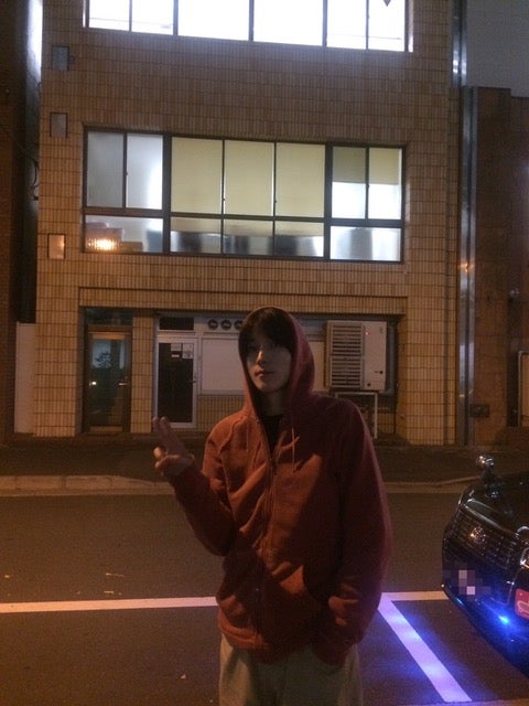 夜の駐車場でピースする四坂亮翔