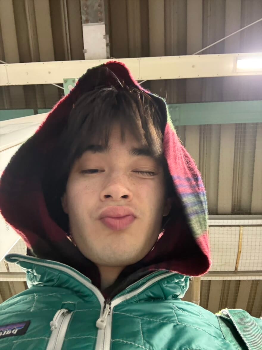 マフラーを巻いてウインクをしている栄莉弥