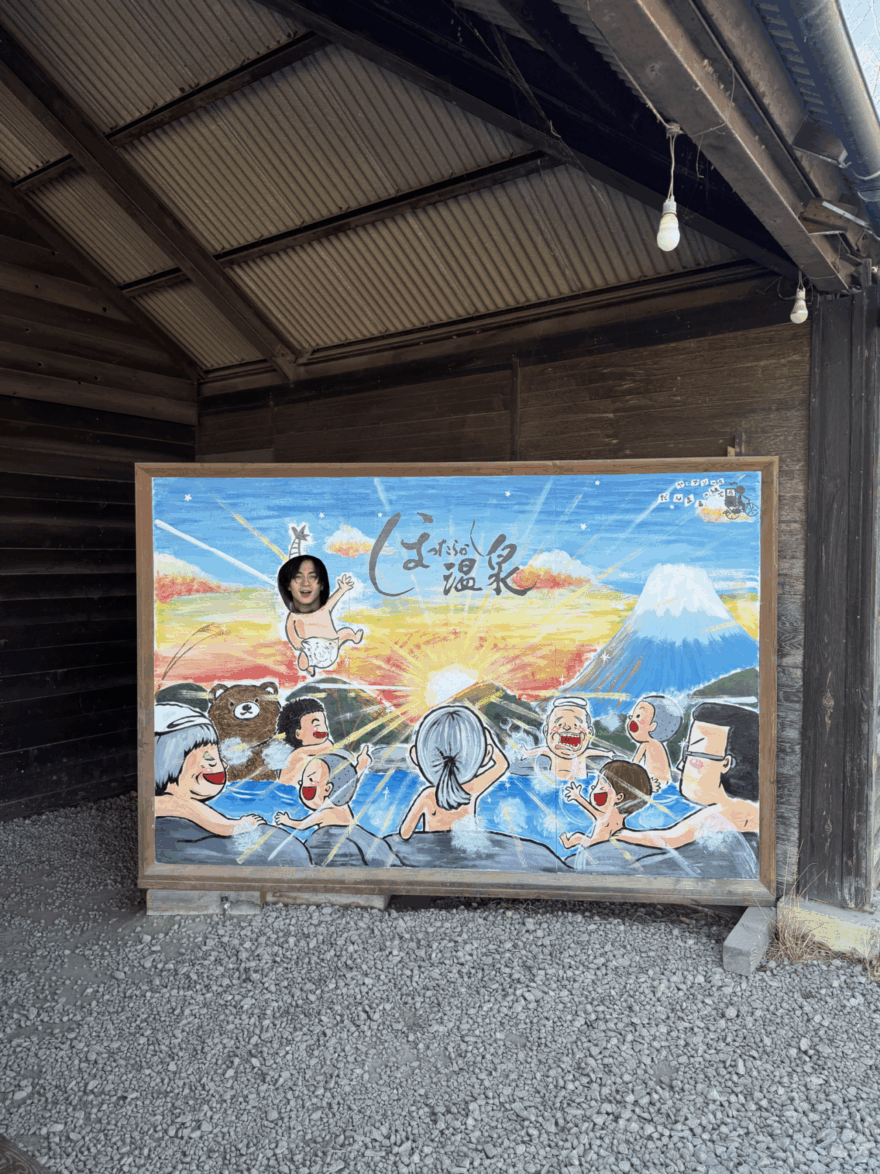 「しま温泉」と書かれた顔出しパネルで遊ぶ松岡