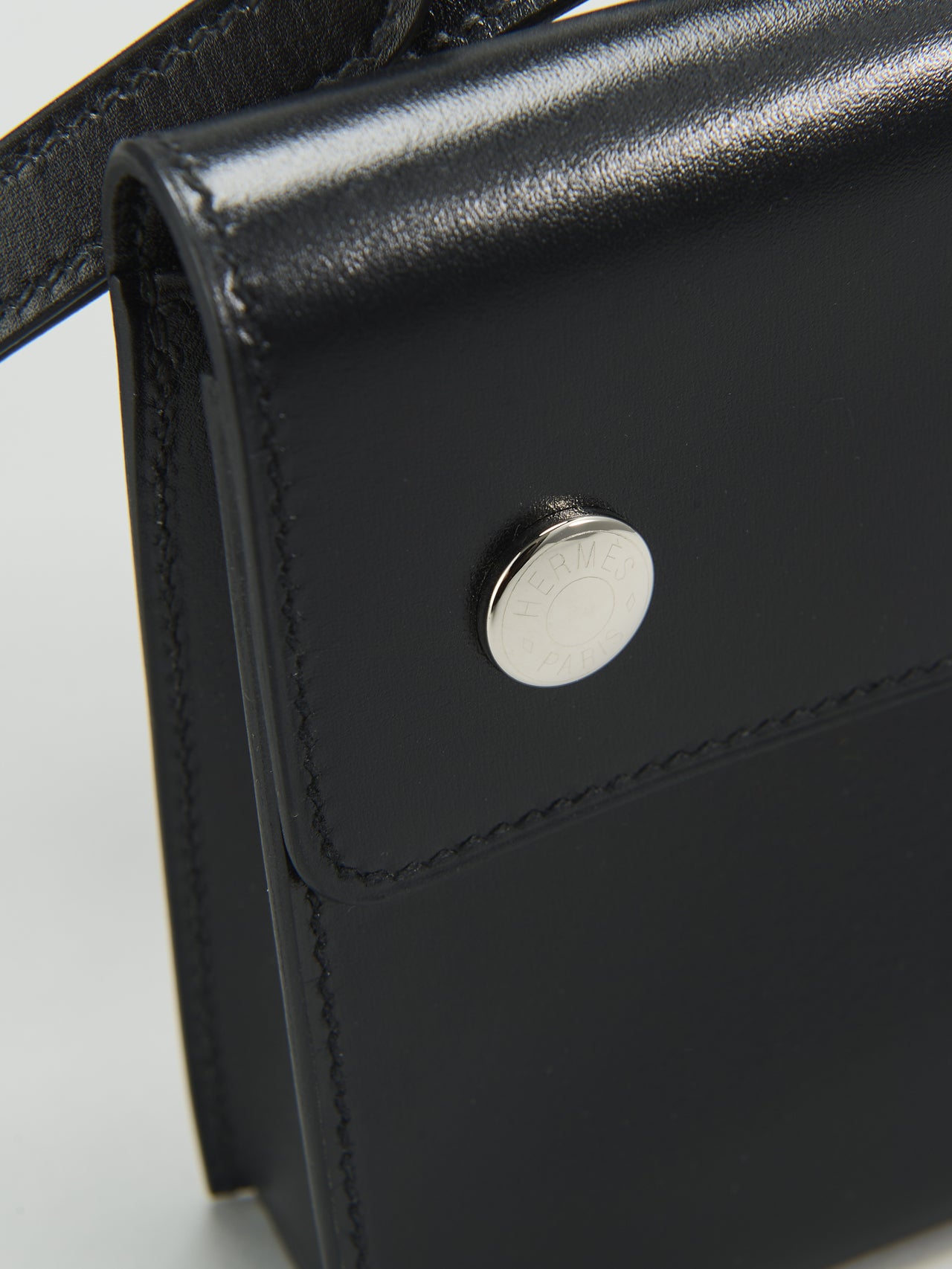 エルメスの黒い「ウォレットバッグ／エルメスナップ」の&ldquo;HERM&Egrave;S PARIS&rdquo;の刻印が施されたクルー・ド・セルのスナップボタン