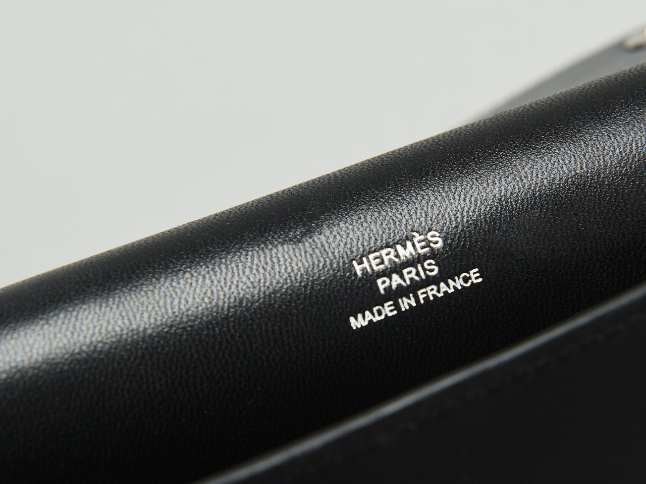 エルメスの黒い「ウォレットバッグ／エルメスナップ」の刻印ロゴ