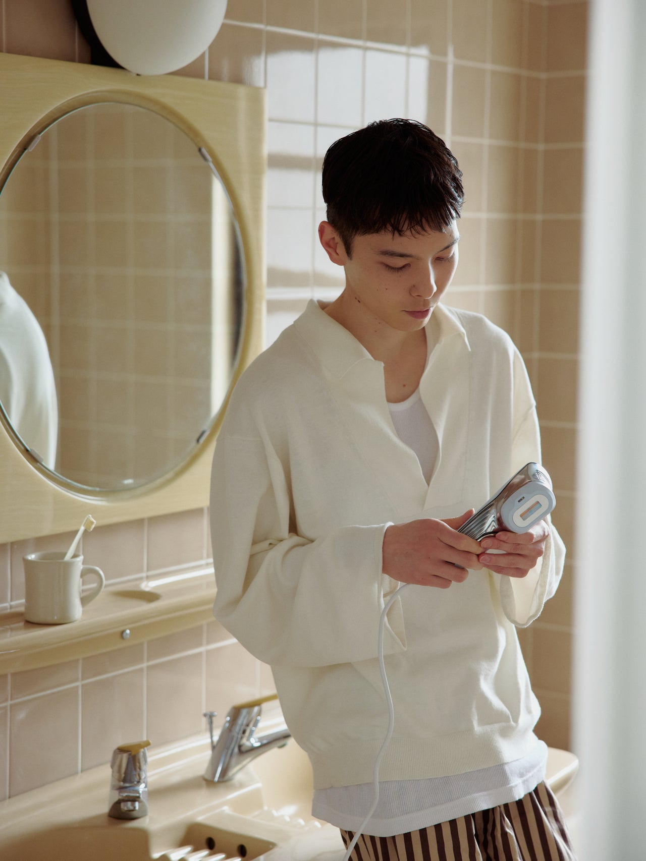 ReFa（リファ）の光美容器「ReFa EPI W COOL」本体を洗面台で手に持つメンズノンノモデルの守屋光治さん