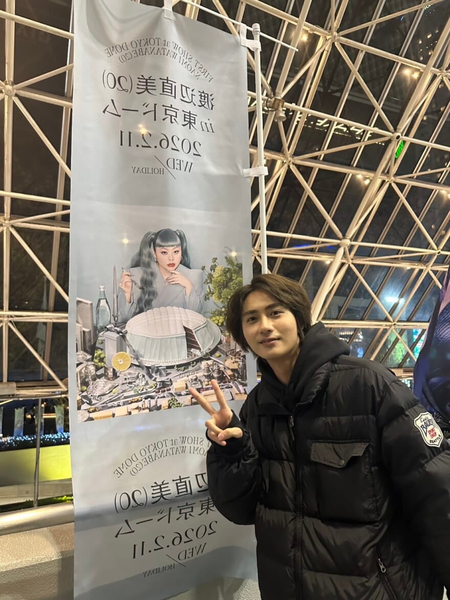 「渡辺直美 (20) in 東京ドーム」ののぼりの前でピースする髙橋大翔