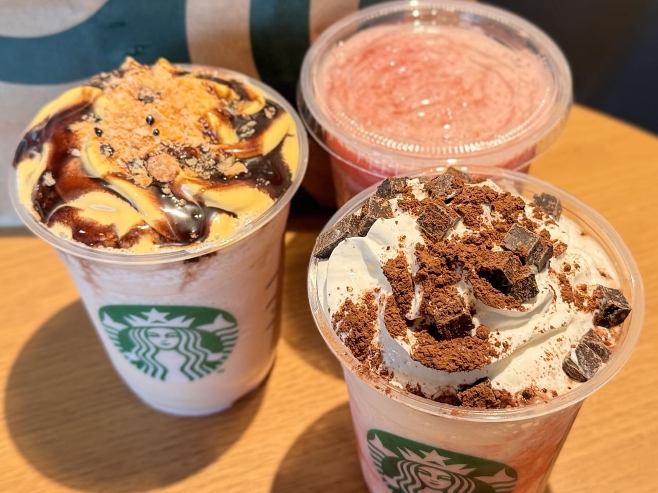 スタバ新作いちご2026『ストロベリー シュークリーム フラペチーノ&reg;』『スターバックス ストロベリー フラペチーノ&reg;』、『ストロベリー ＆ パッション ソルベ ティー』が横に並んだ様子トッピングアップ