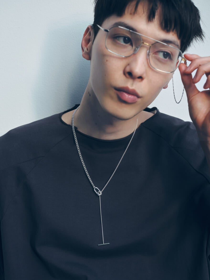Jouete（ジュエッテ）のネックレスと、チェーンつき眼鏡を着用する守屋光治