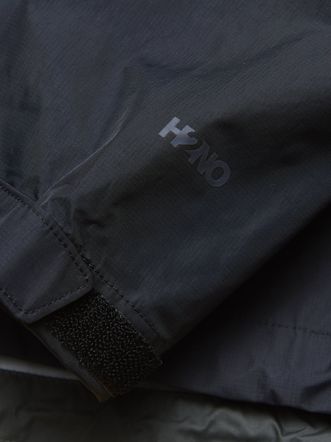 パタゴニアの黒いメンズ・トレントシェル 3L・レイン・ジャケットのロゴ