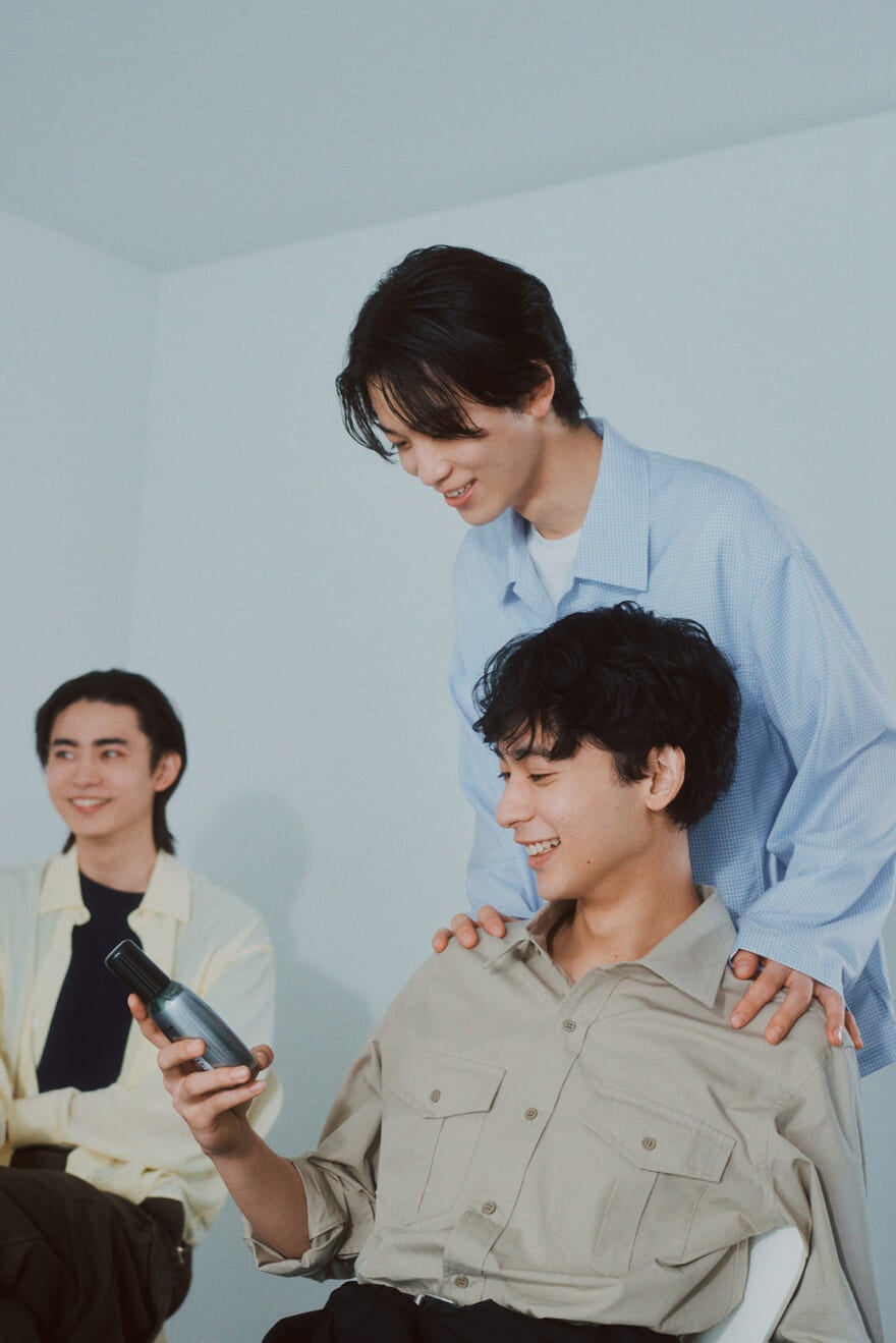 ウーノ(uno)の4Dスカルプエッセンスを手に取る松井大奈さんと小方蒼介さん、それを見守る豊田裕大さん