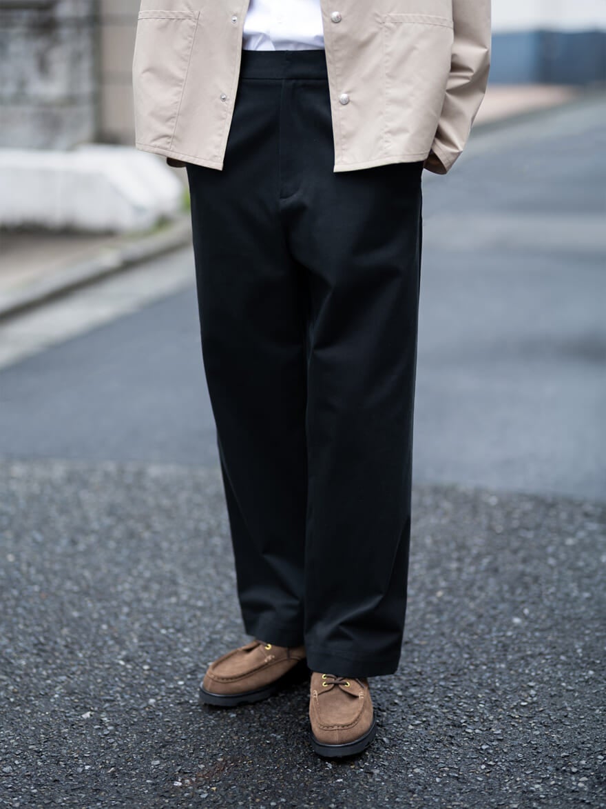 「ユニオンスラック」のワイドストレートのブラックパンツと、ベージュのブルゾンのコーディネート