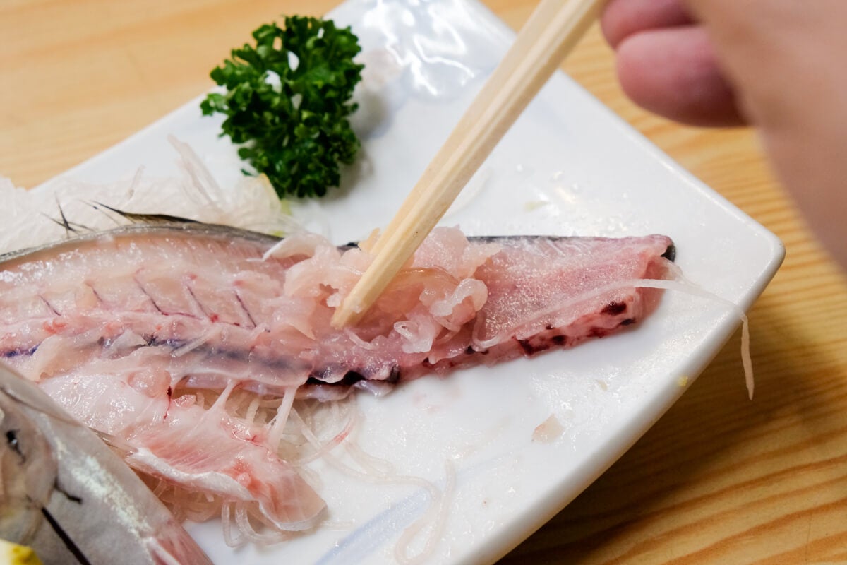 東京都板橋区『やまだや』骨の周りについた身を掻き出して食べている様子