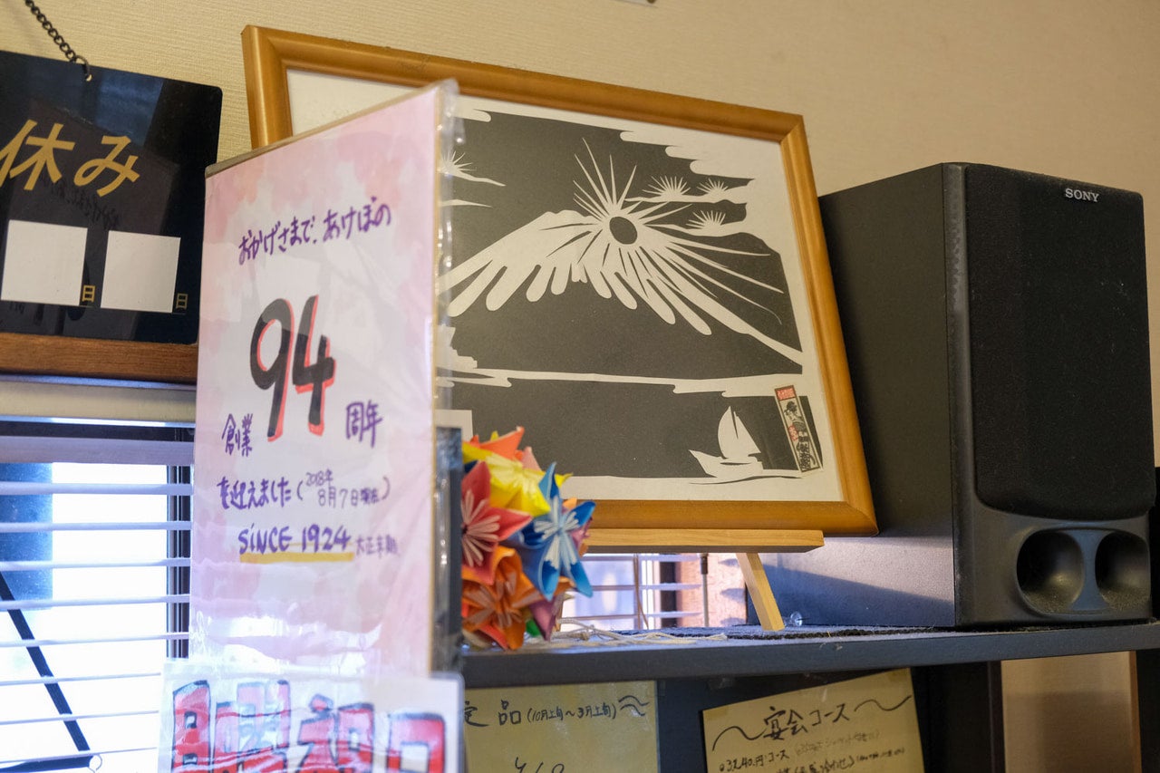 千葉県・習志野市「レストランあけぼの」お店のレジ横飾られた、創業からの年数が書かれた色紙と、「お客さんつながりで作ってもらった」という屋号を象徴する一枚の版画