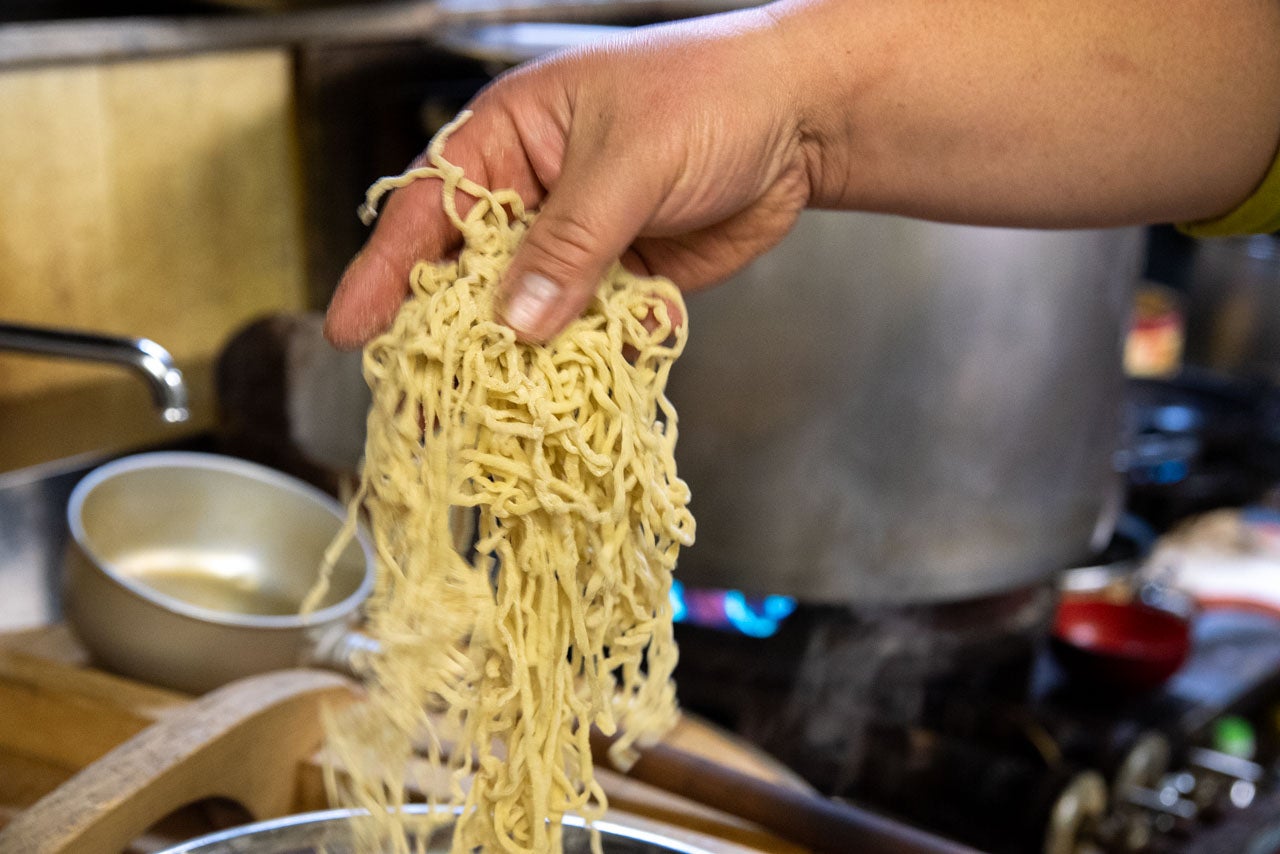 青森県つがる市『神武食堂』麺を鍋に入れている手元