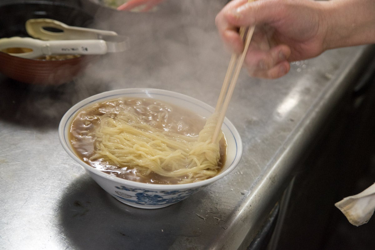 青森県青森市『小田九』皿に盛った麺を湯がいている様子