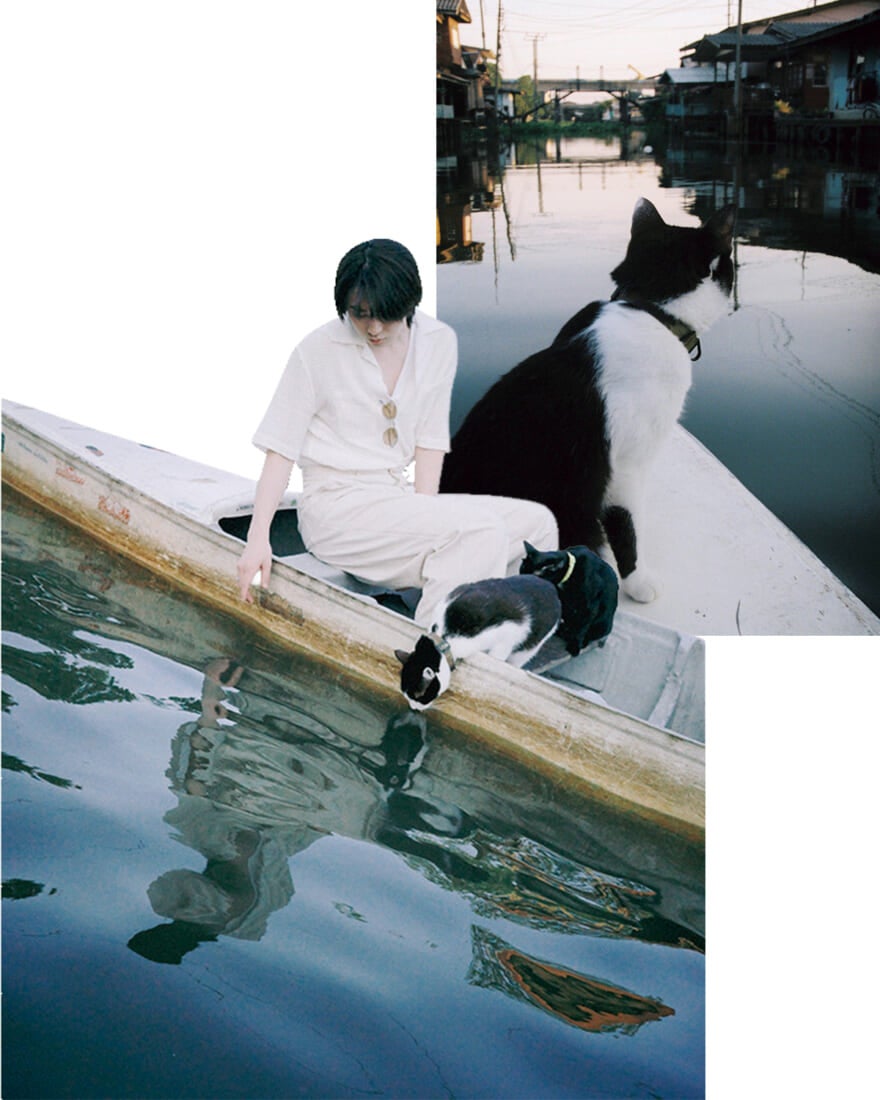 ボートから運河をのぞきこむ豊田と猫