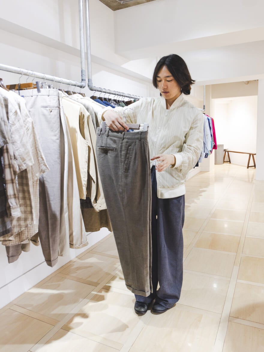 チェック柄のパンツを手に取る根本さん