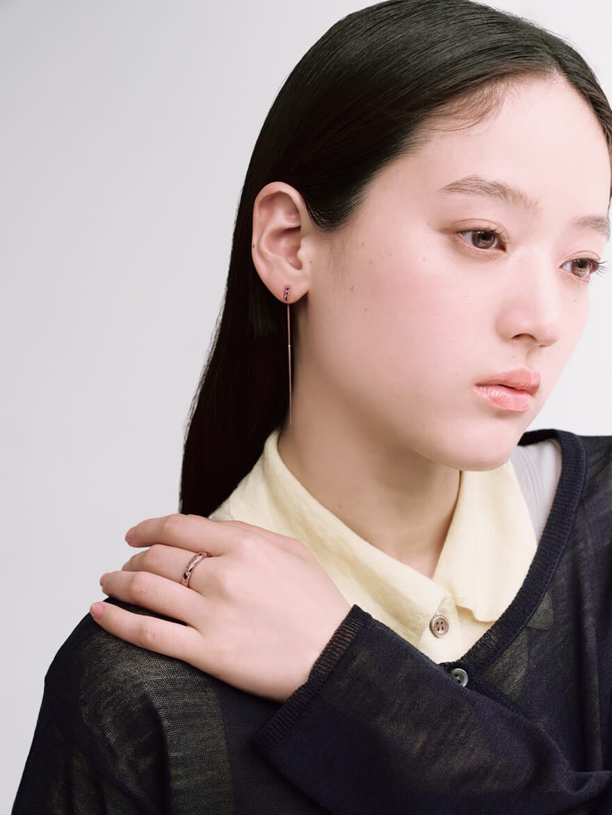Jouete(ジュエッテ)のピンクゴールドのチェーンピアスとリングを着用する女性モデル