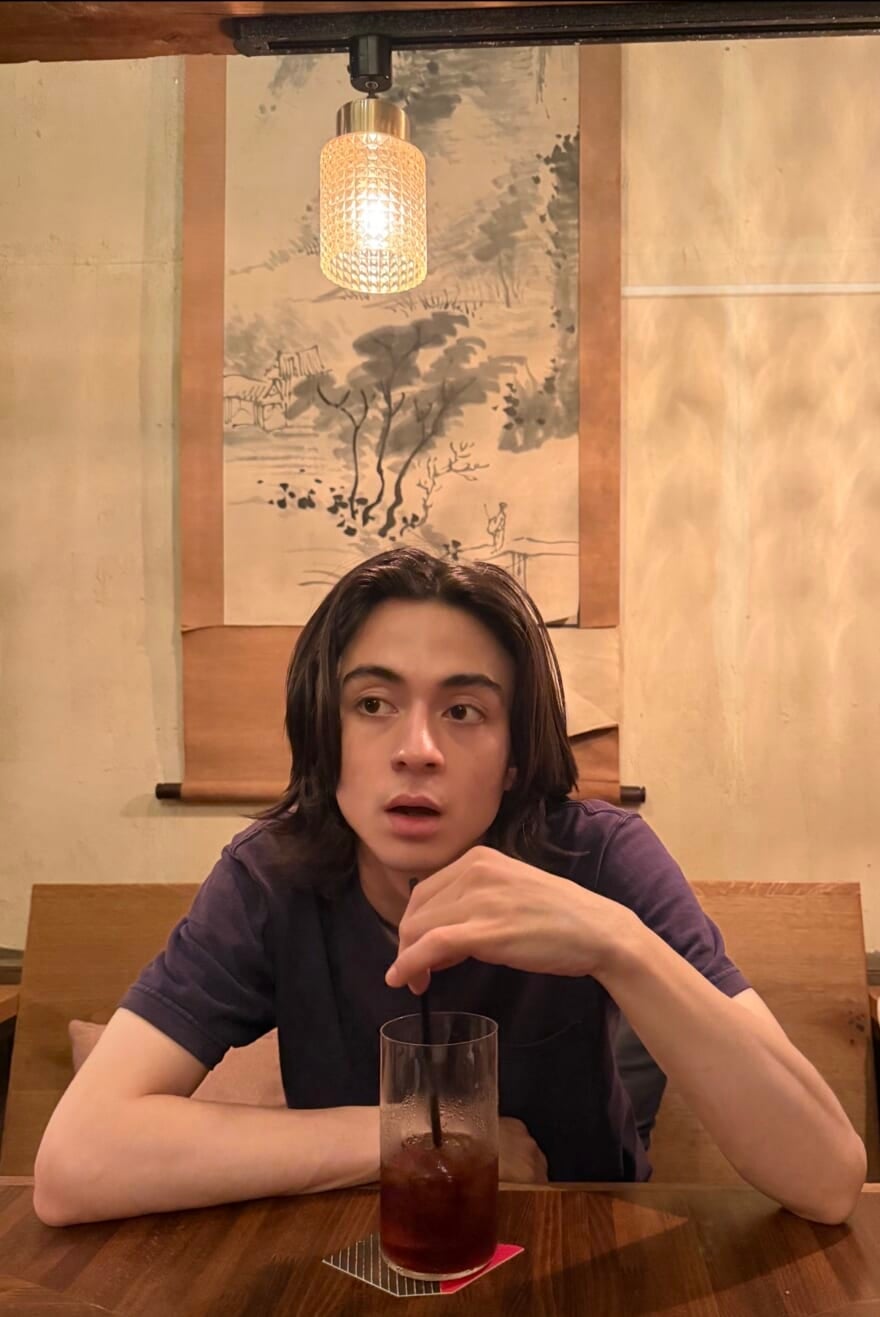 掛け軸の前にいる松岡光